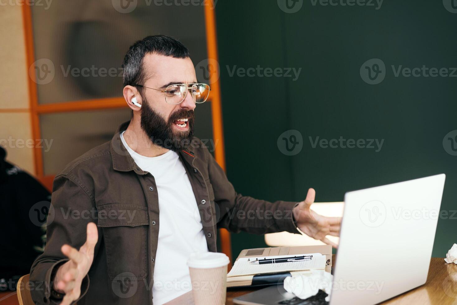 Angry caucasian male freelancer in cafe having quarrel during web camera conversation discussing problems with online business project, nervous looking man is talking online. photo