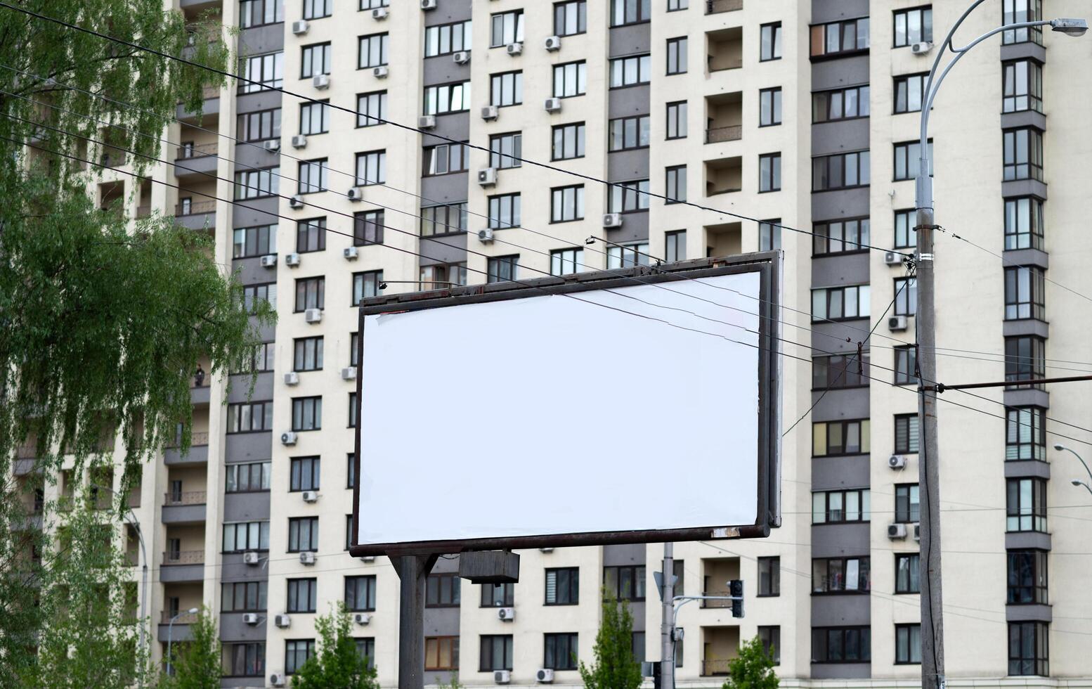 Blank white advertising billboard near residential buildings in the city on a summer day. photo