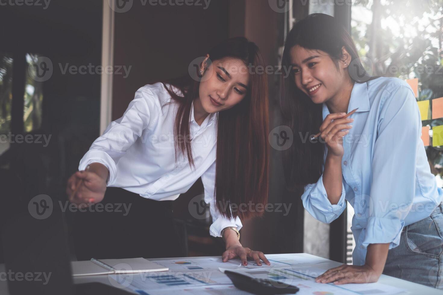 Diverse team of young business people dressed in formal wear cooperating on developing common design project and call by laptop computer. photo