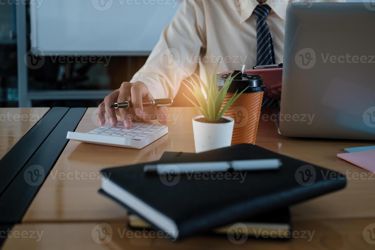 Young accountant man analyzes financial data using calculator and laptop computer to compute and summarize big data for present on conference. financial concept. photo