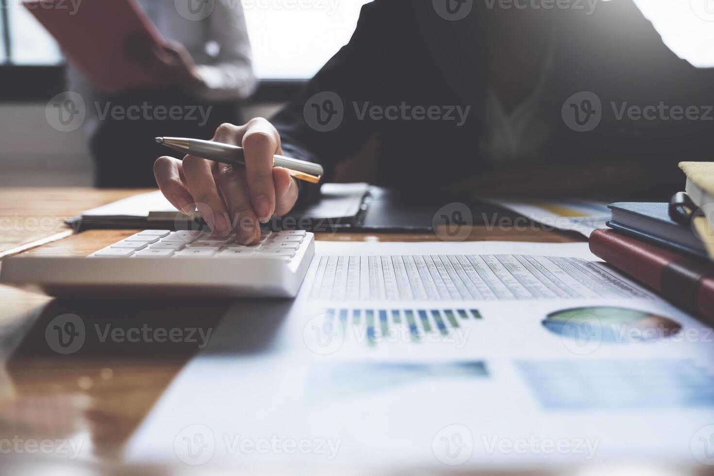 Project management team updating and calculating financial chart on paperwork, two business people in office. photo