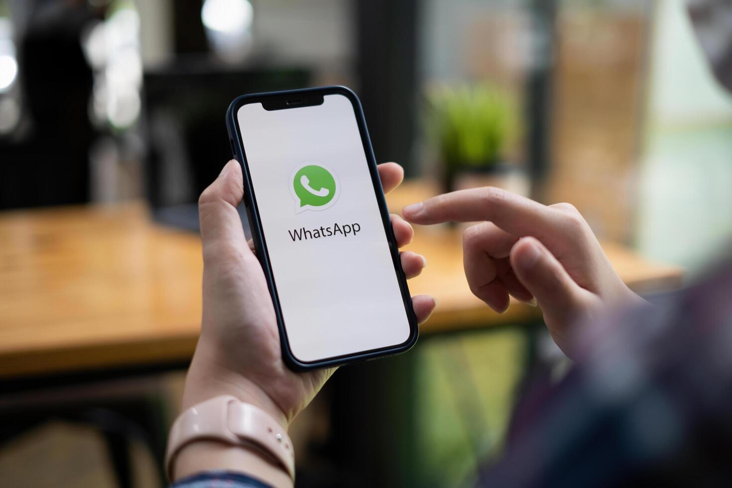 CHIANG MAI, THAILAND - JULY 15 2021 . Man holding a iPhone and open appstore searching social Internet service WhatsApp on the screen. iPhone was created and developed by the Apple inc. photo