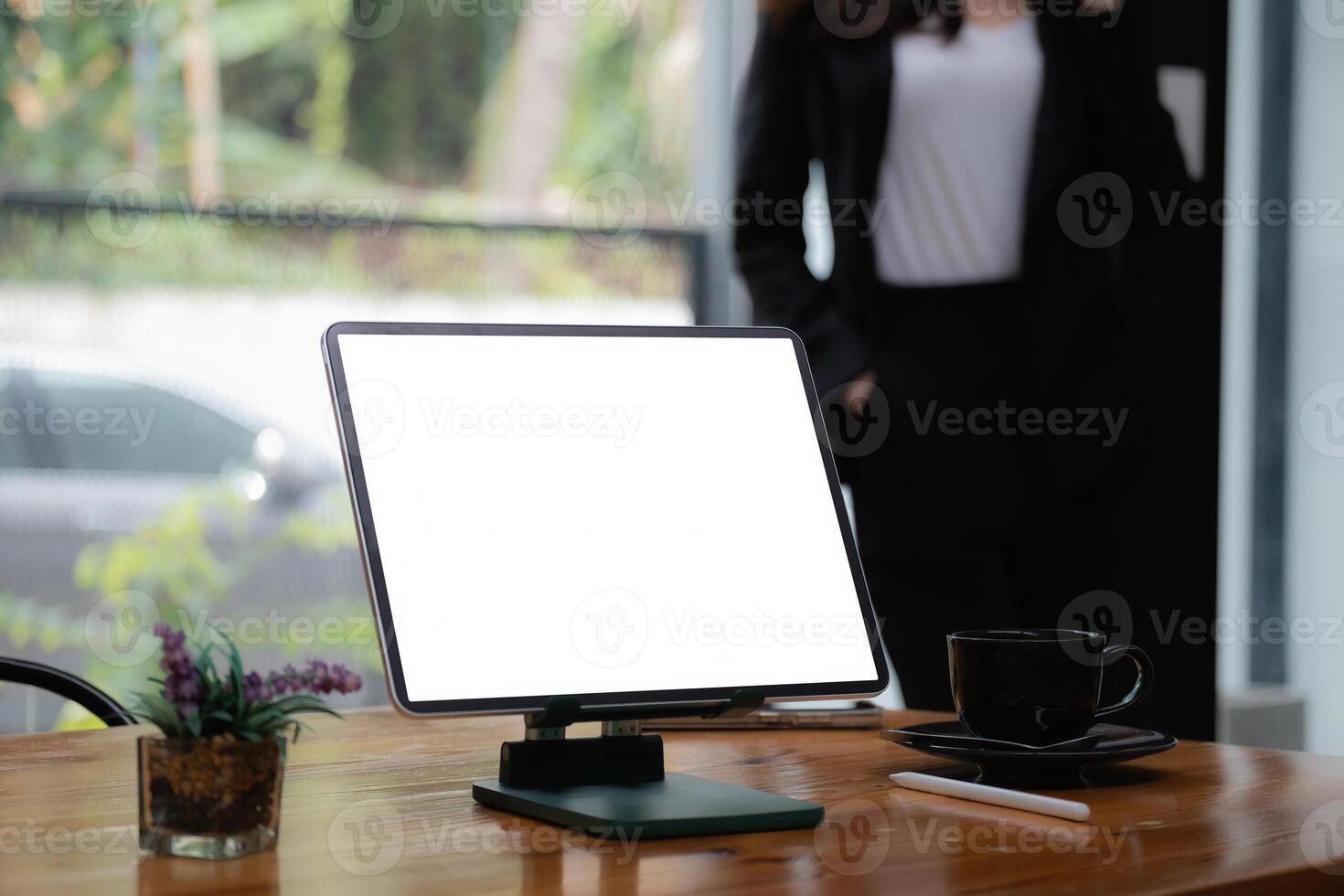 Mockup digital tablet on wooden desk with blank screen. Business people working at background. photo