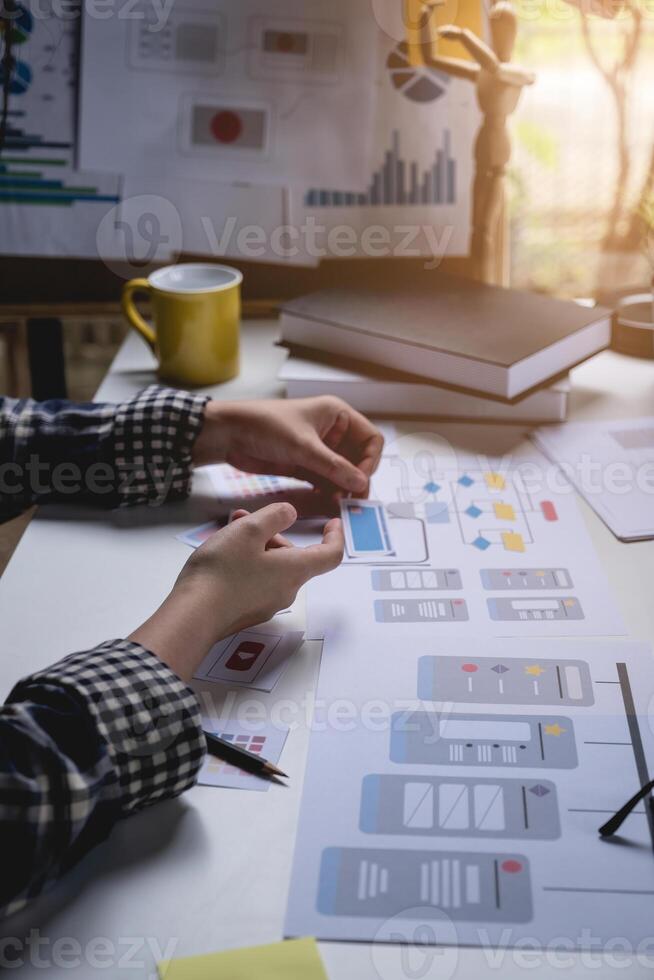 Rear view developer ux and ui designer about mobile phone app and choosing some interface to mockup phone. Creative digital development agency concept. photo