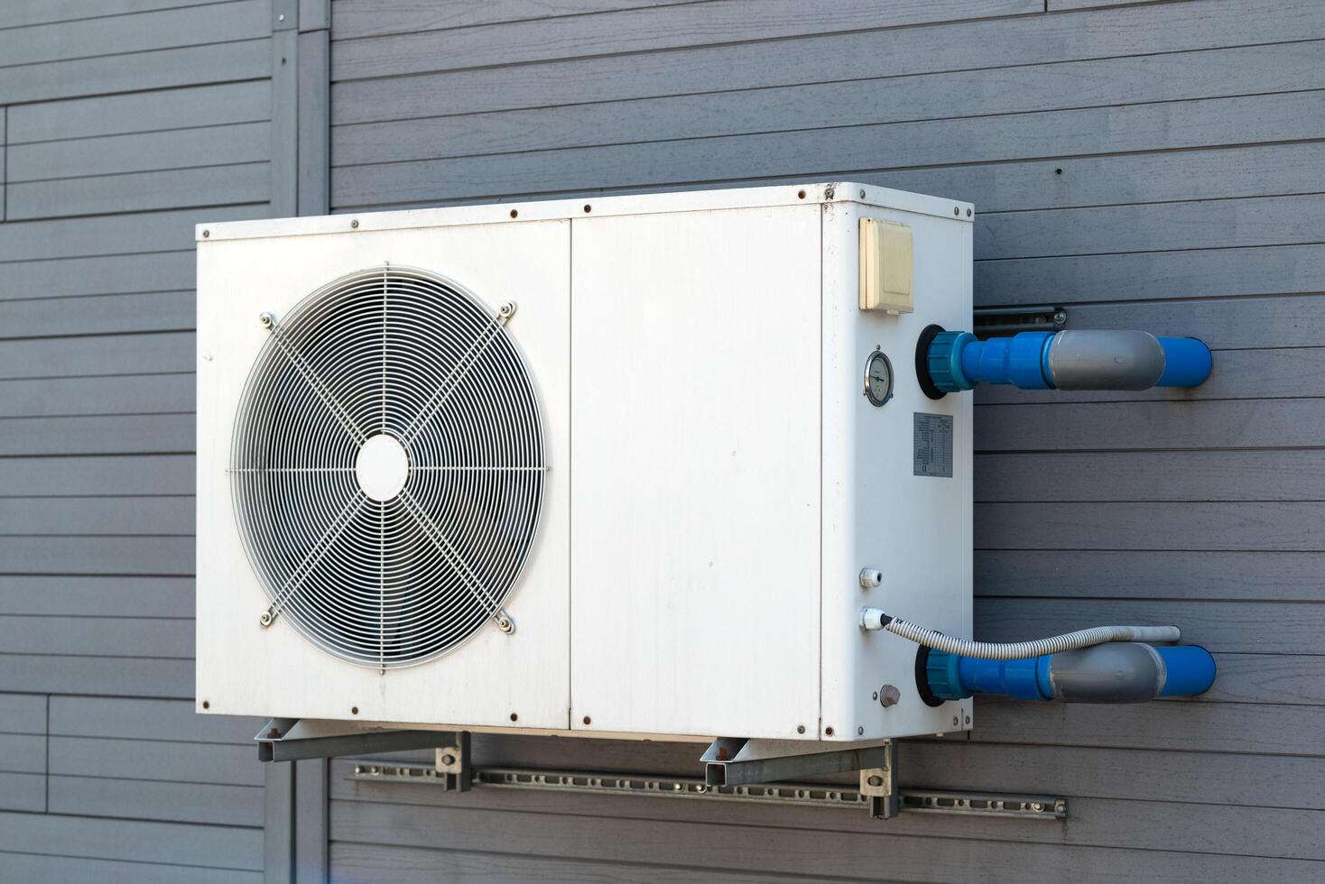 Condensing unit of air conditioning systems. Condensing unit installed on the gray wall. photo