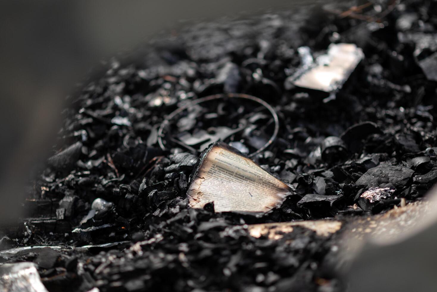 A burnt book on a pile of ashes, the remains of pages in a burnt house. photo