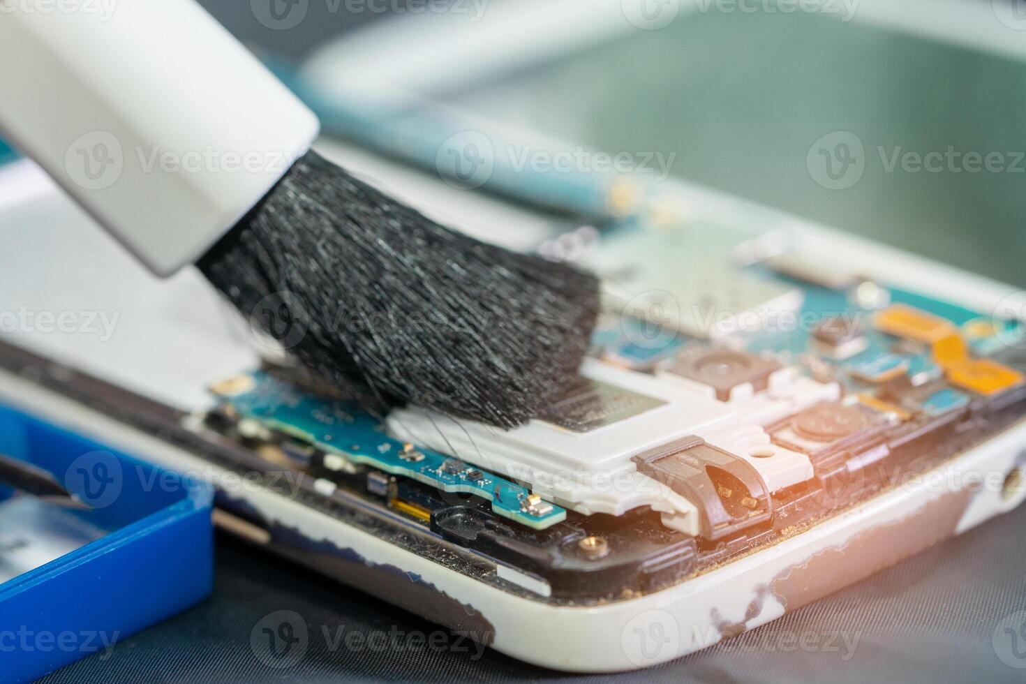 Asian technician repair and cleaning dirty micro circuit main board of smartphone electronic technology with brush, hardware, mobile phone, upgrade. photo
