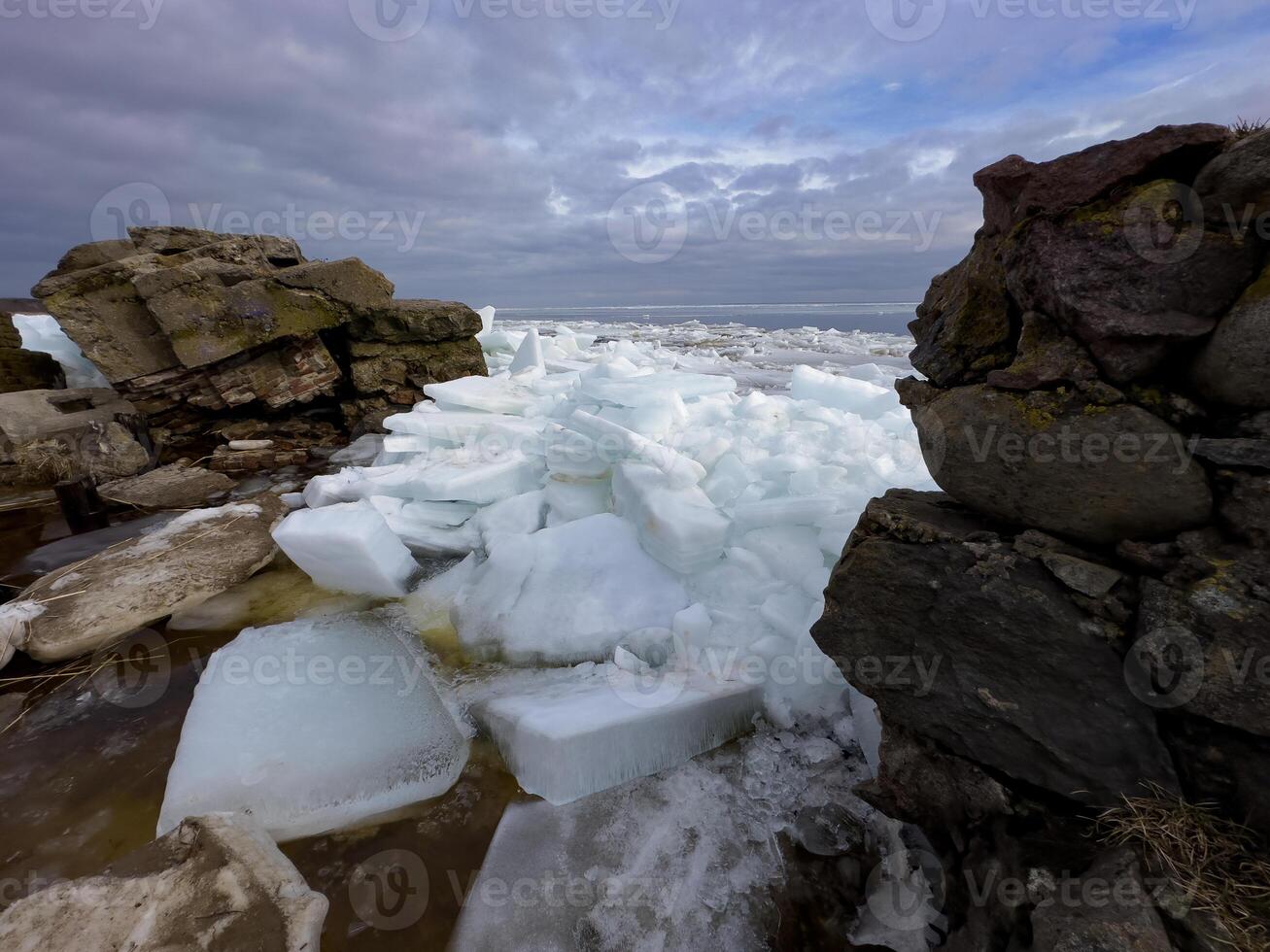 Crystalline ice sheets fracture and float on Russia's Lake Ladoga, capturing the stark beauty of spring's thaw under a clouded sky. photo