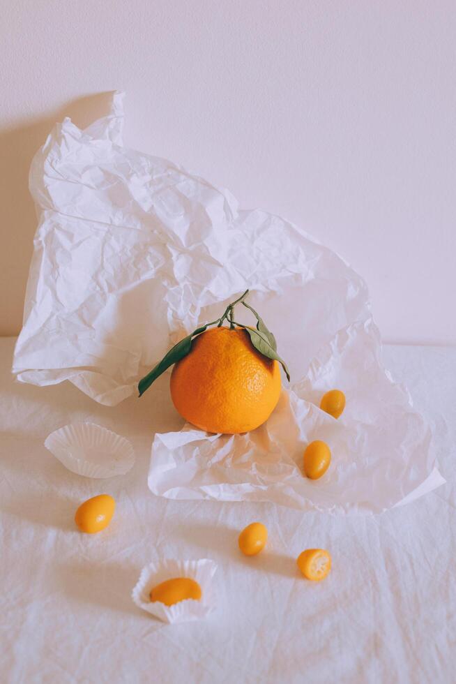 Fresh juicy citrus fruits with green leaves on white craft paper. photo