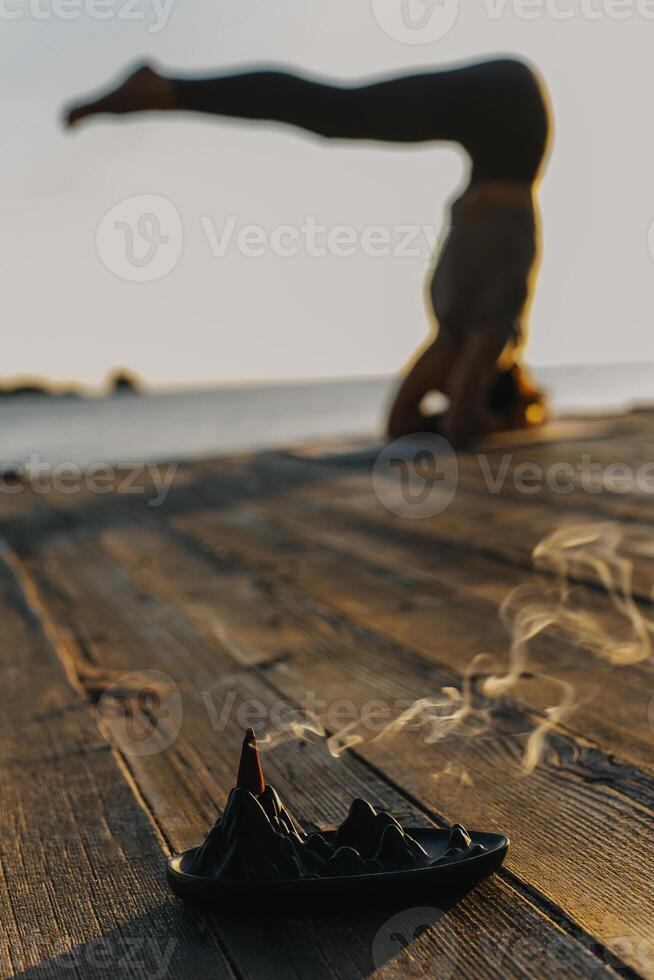 Girl practicing yoga and meditating on the beach at sunset. photo