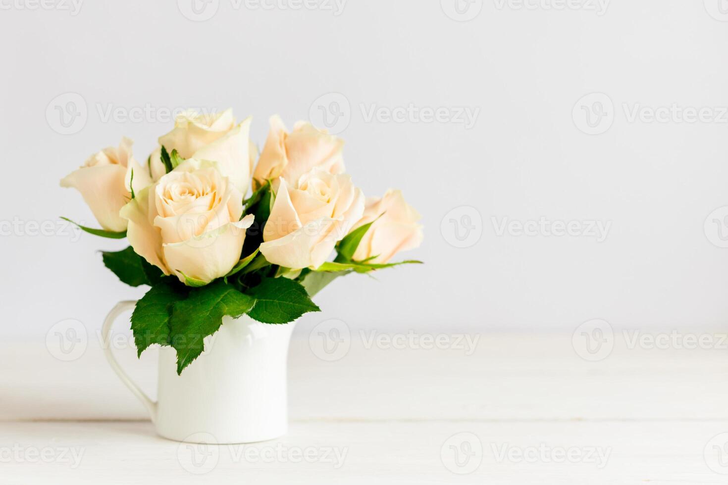 Romantic bouquet of pastel cream roses in a jar on a white background. photo