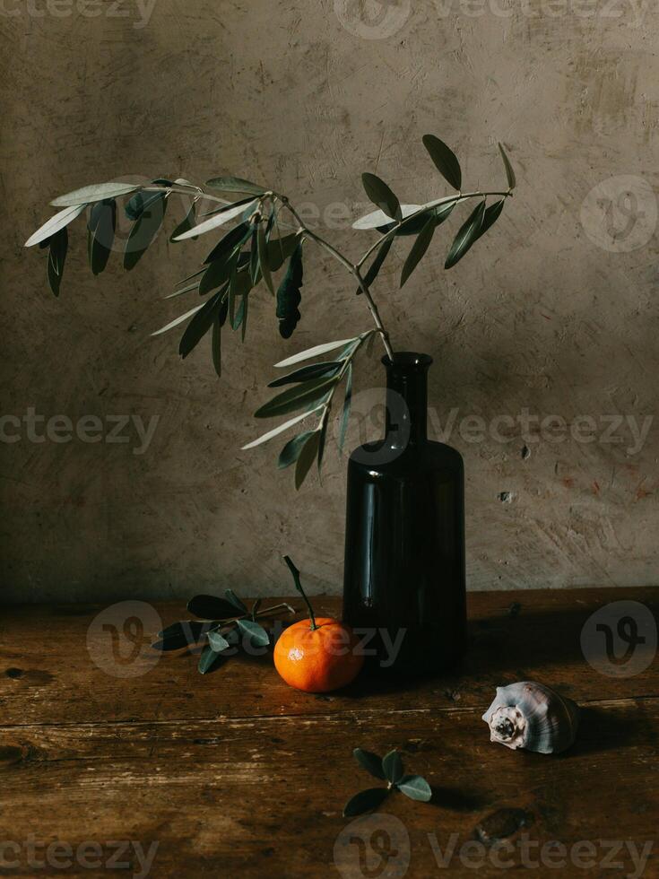 Still life with olive branch and tangerines. Dark rustic background. photo