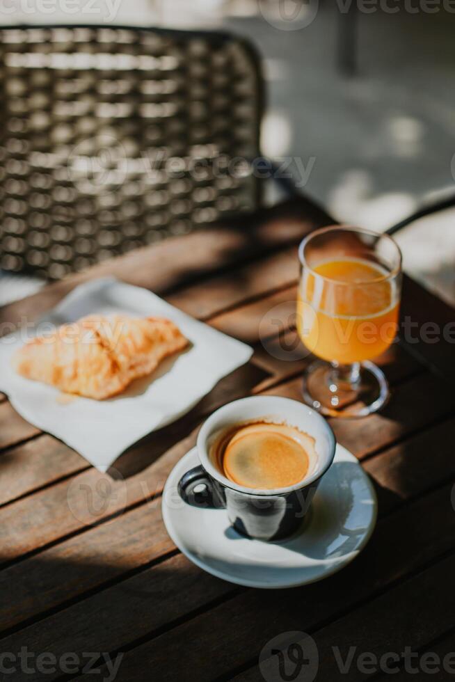 Cup of black coffee, a croissant and glass of fresh orange juice on a table in a street cafe. photo