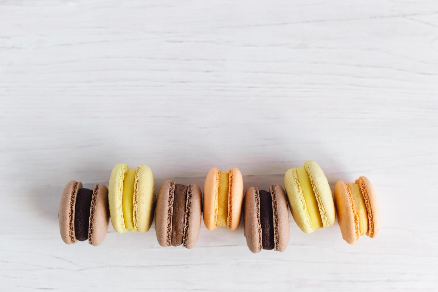 sabroso francés macarons en un blanco de madera mesa. blanco fondo, pastel colores. foto