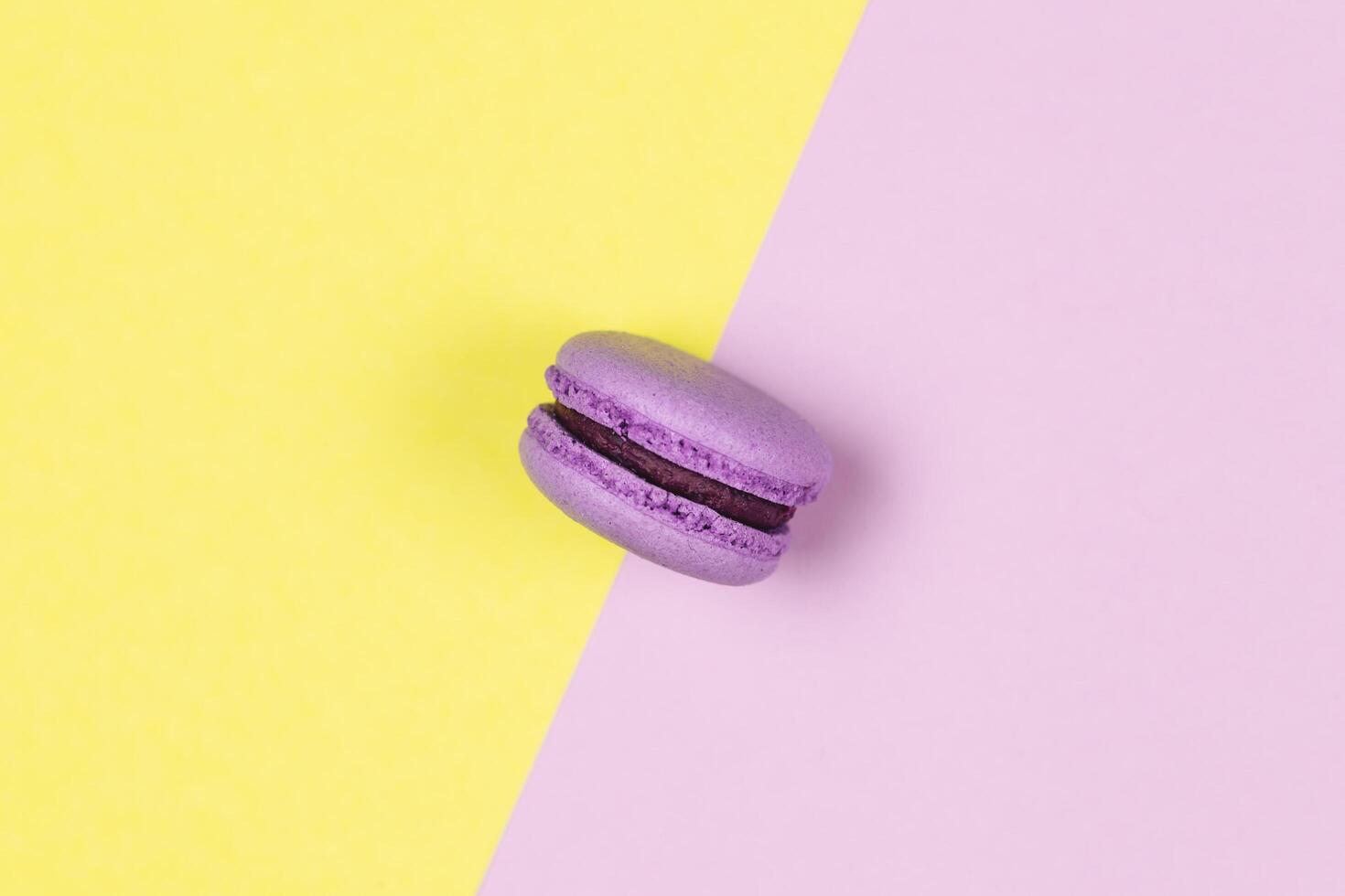 Purple french macaron on a yellow and purple background. photo
