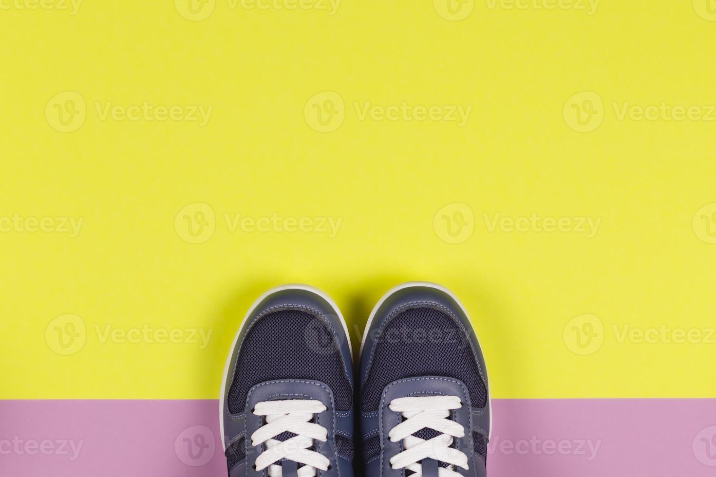 Grey sneakers on the violet and yellow background. Concept for healthy lifestyle and everyday training. photo