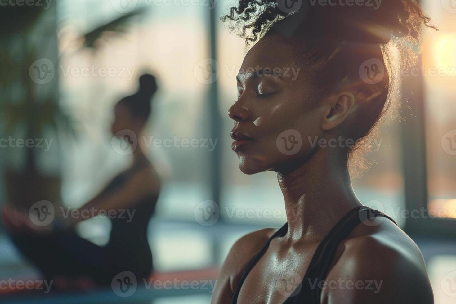 Young women sitting and meditating with eyes closed. Blurred yoga studio on background. photo