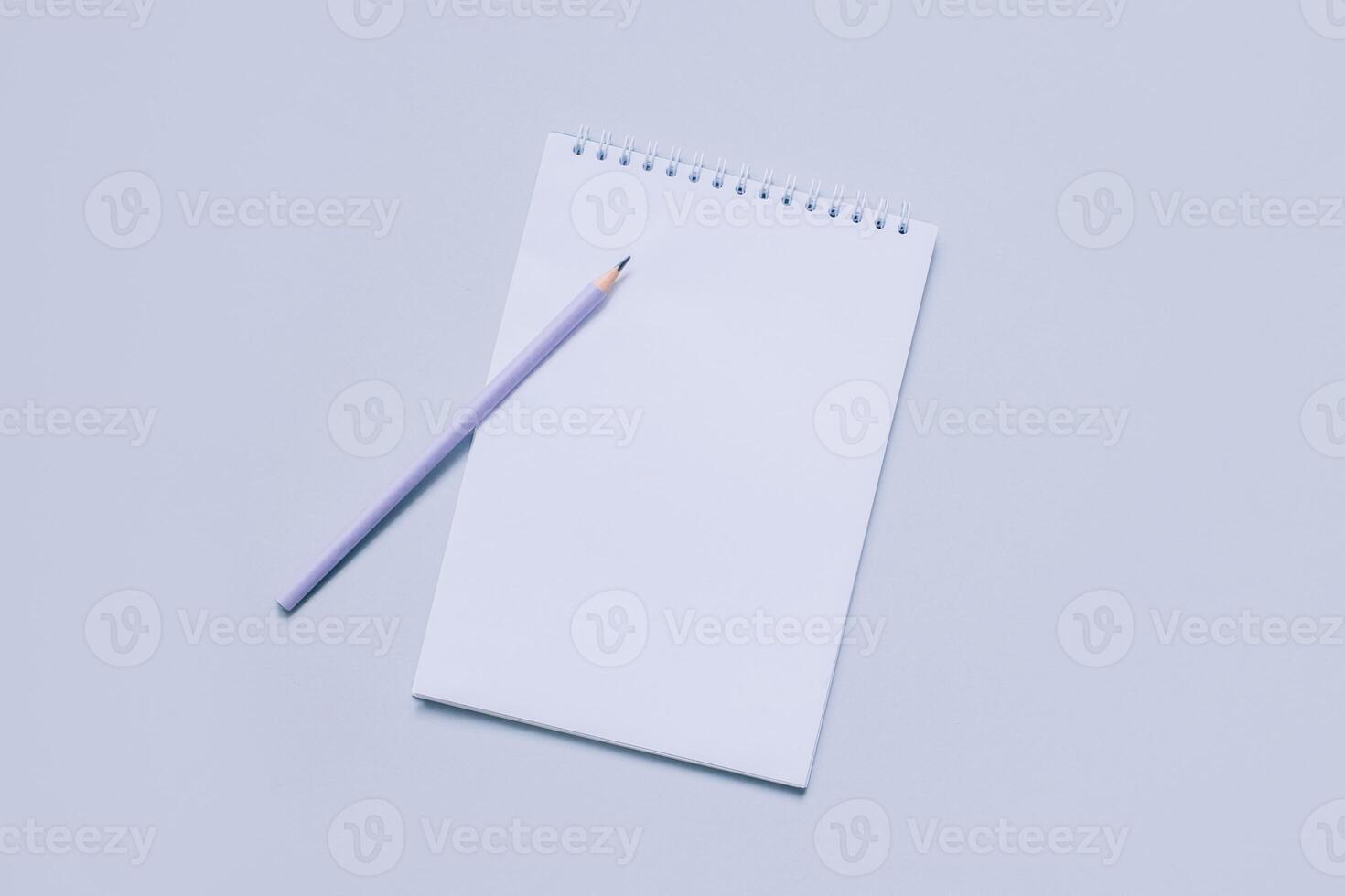 Notebook with blank page and pencil on light purple background. photo