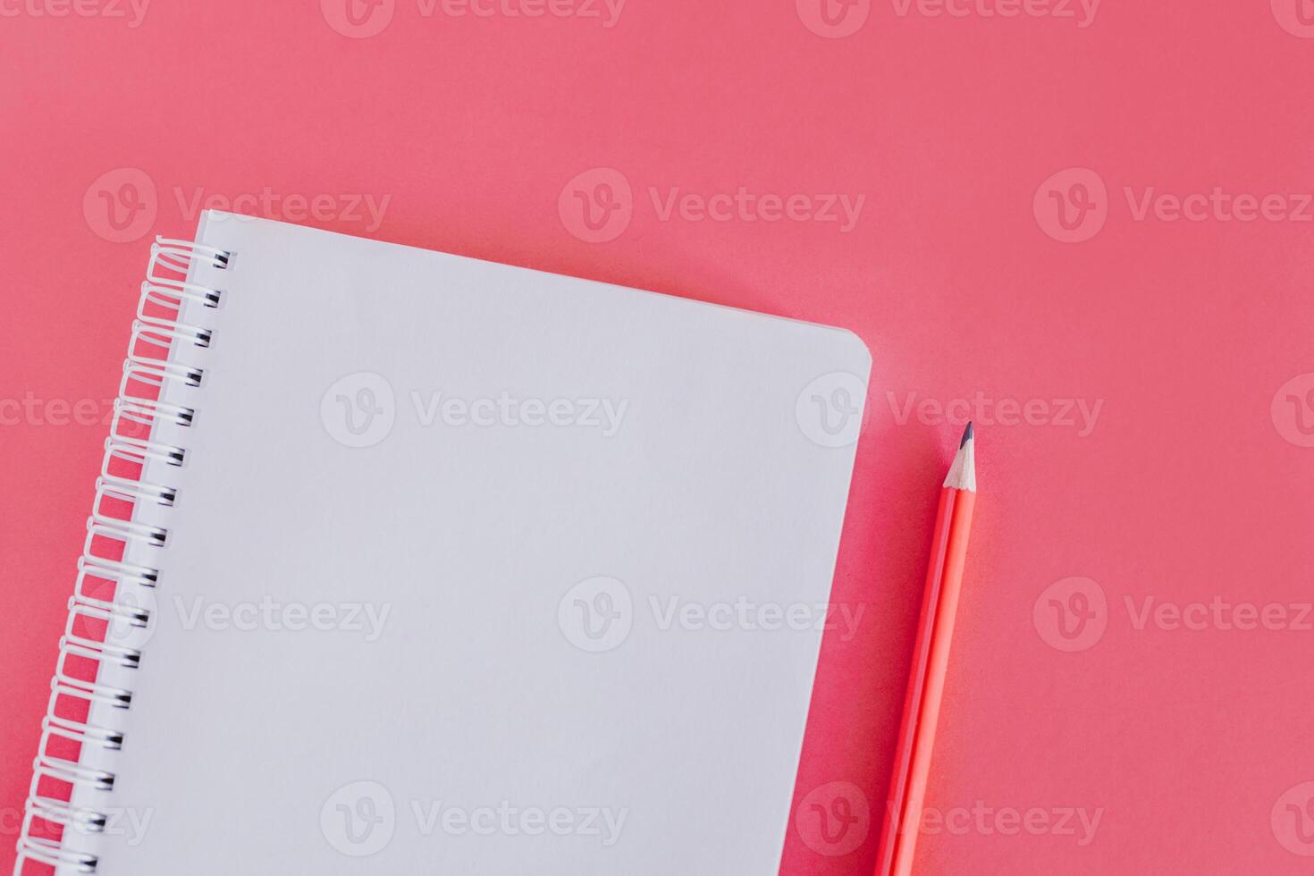 Notebook with a blank page and a pencil on pink background. photo