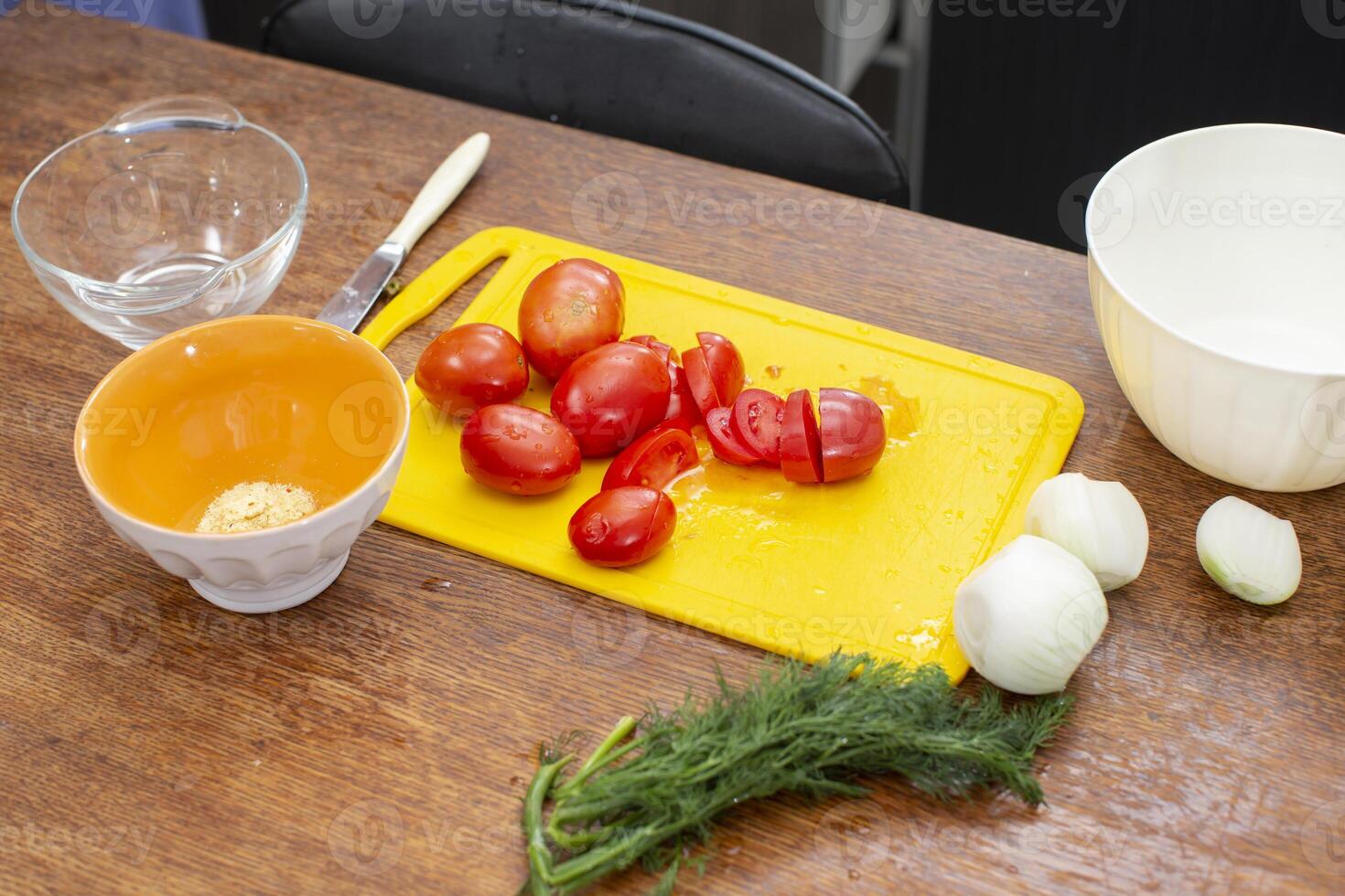 There is a cutting board with tomatoes and onions on the table. Prepare vegetable salad. photo
