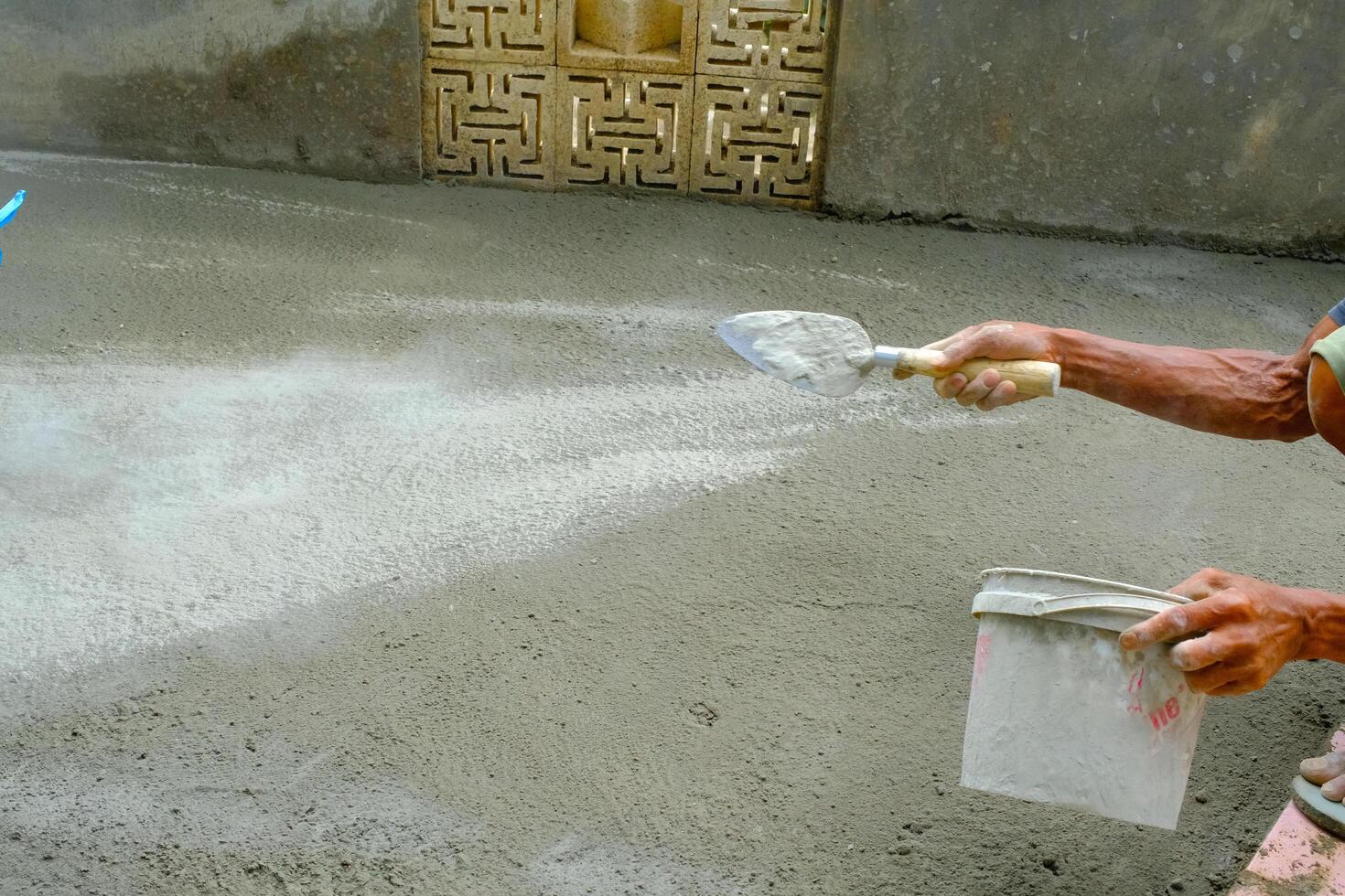 Industrial Photography. The hands of a dark-skinned worker are sprinkling cement powder onto the cast floor. Sprinkling cement to harden the castings. photo