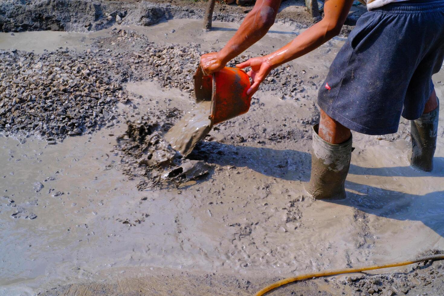 Industrial Photography. Construction work activities. Workers are hoeing and mixing cement with sand and stones for cement castings. Bandung - Indonesia, Asia photo