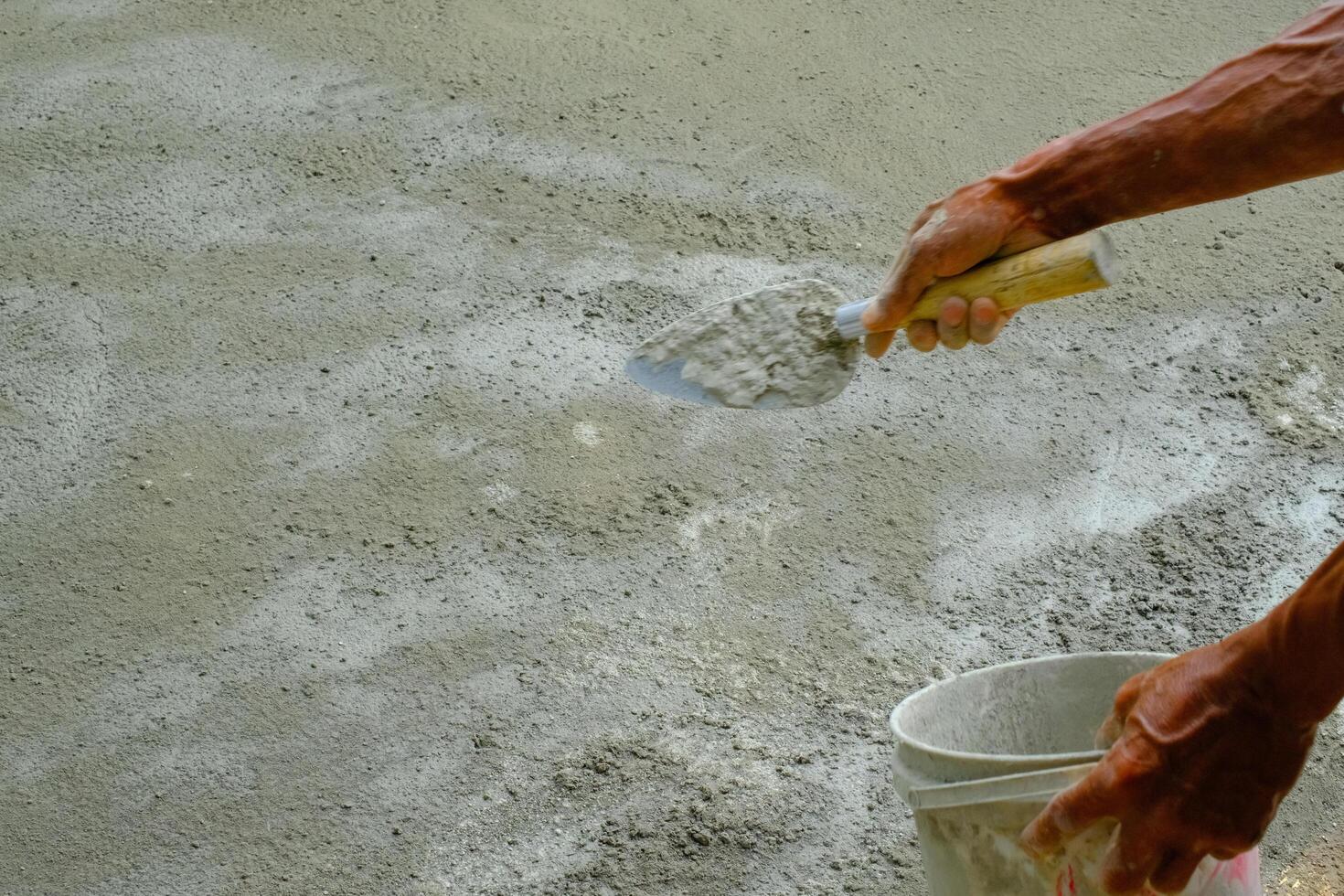 Industrial Photography. The hands of a dark-skinned worker are sprinkling cement powder onto the cast floor. Sprinkling cement to harden the castings. photo