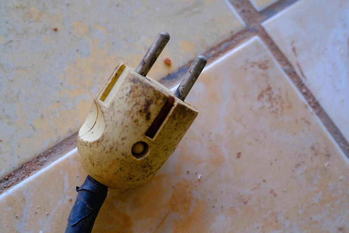 Industrial Photography. Construction Tools. Isolated worn electric plug with blue wire. A cable plug on the floor. Bandung, Indonesia photo