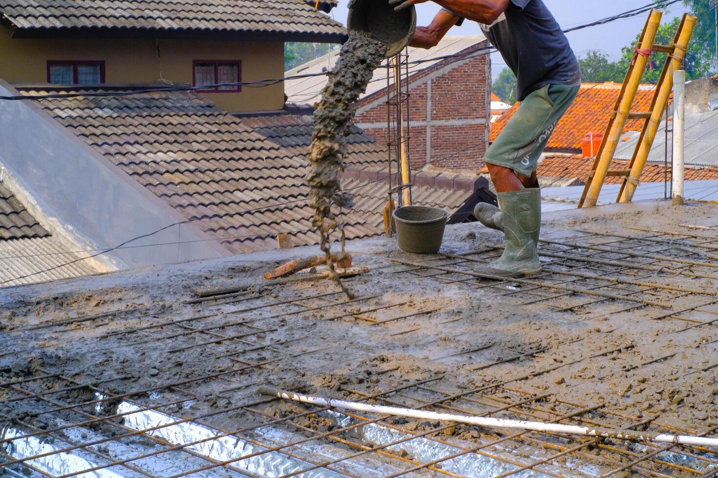 Industrial Photography. Construction work activities. A worker is pouring cement into wire mesh during the floor pouring process. Bandung - Indonesia, Asia photo