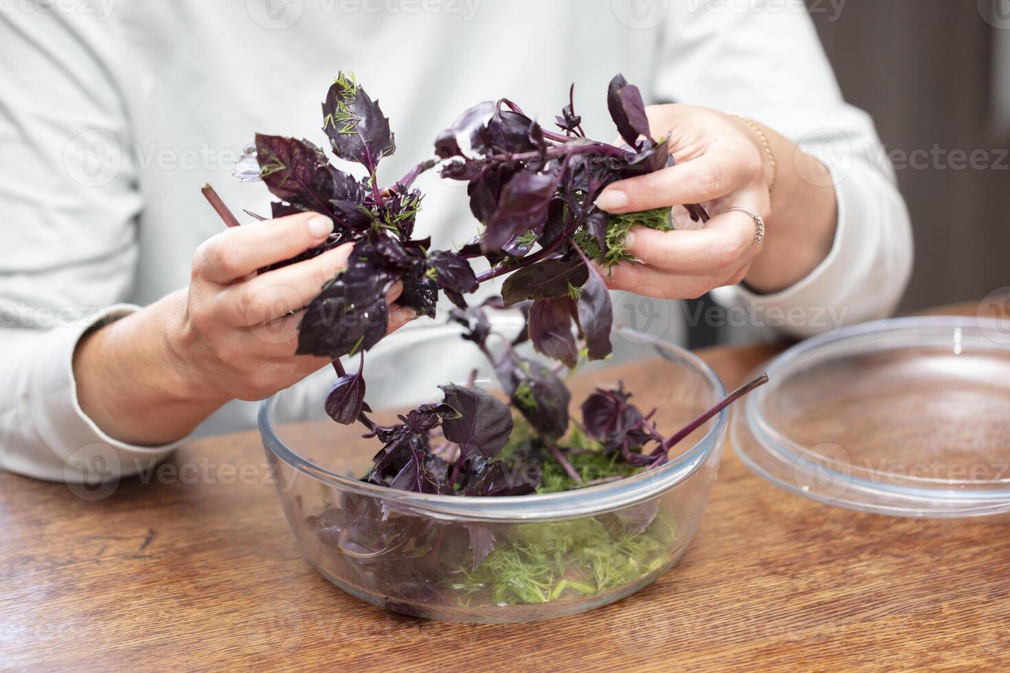 manos preparando ensalada. ordenar fuera el albahaca ramitas hierbas en cocinando. foto