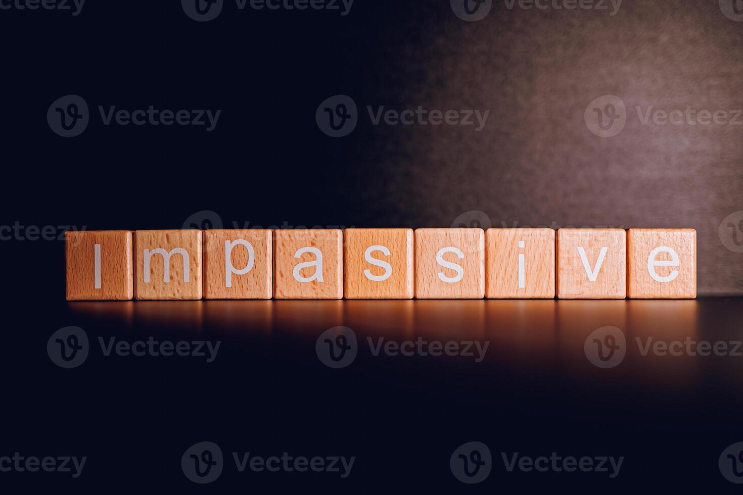 Wooden blocks form the text Impassive against a black background. photo