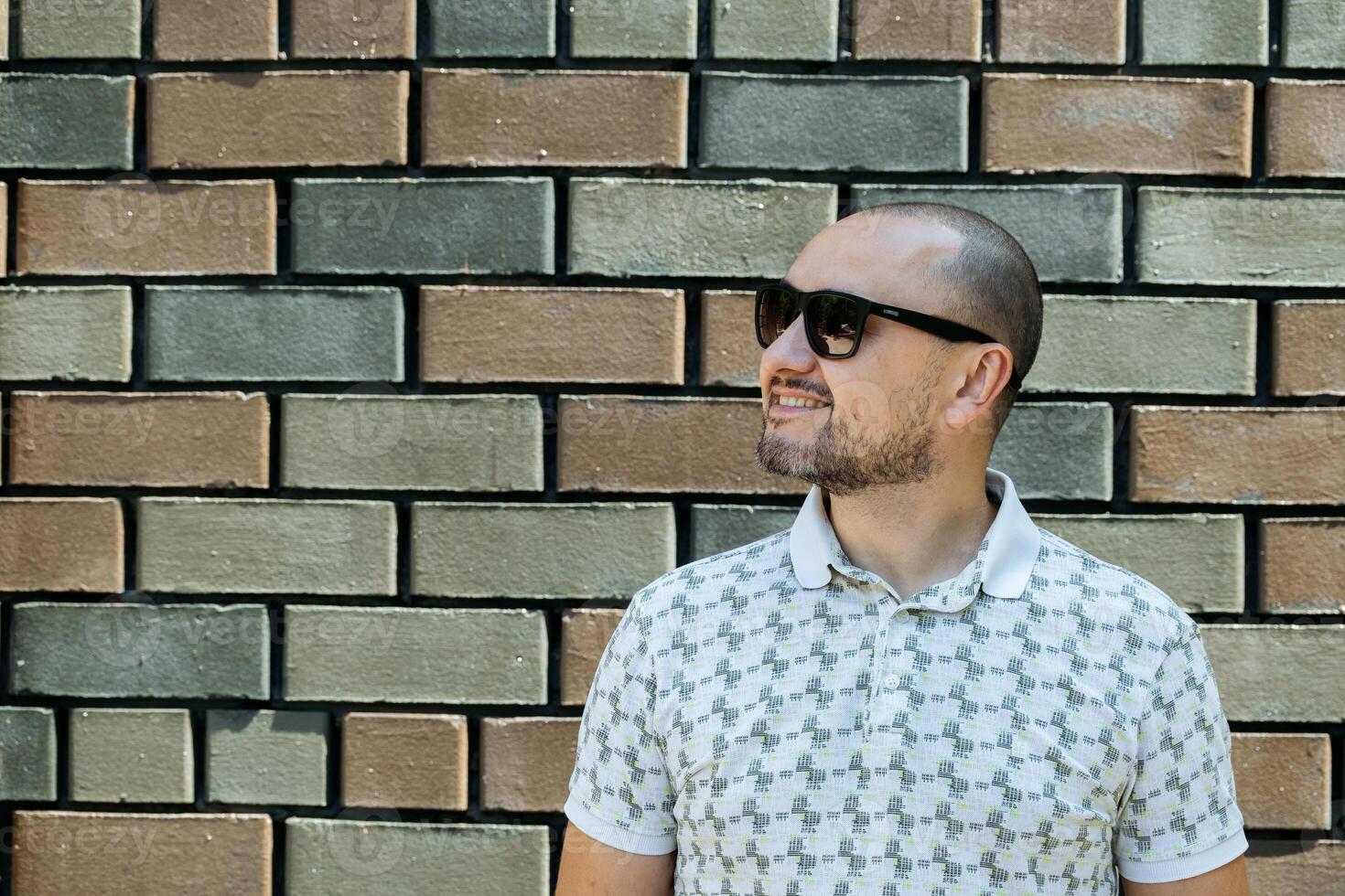 Smiling Man with Sunglasses Against Wall photo