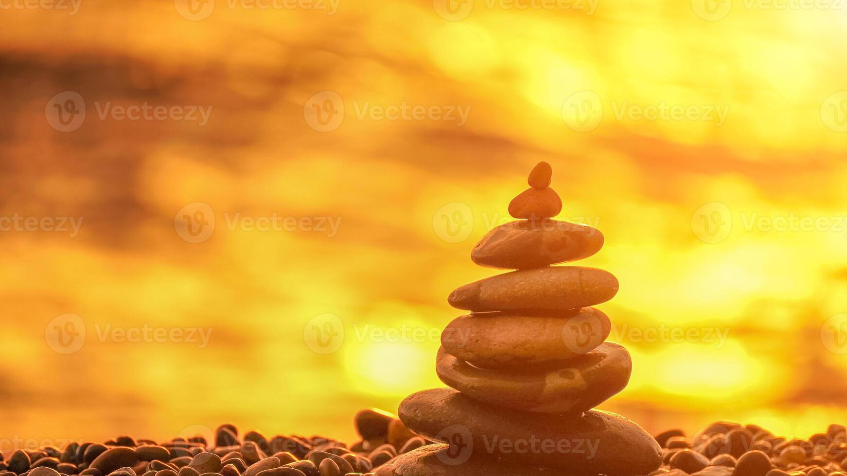 Balanced rock pyramid on pebbles beach. Golden sea bokeh on back photo