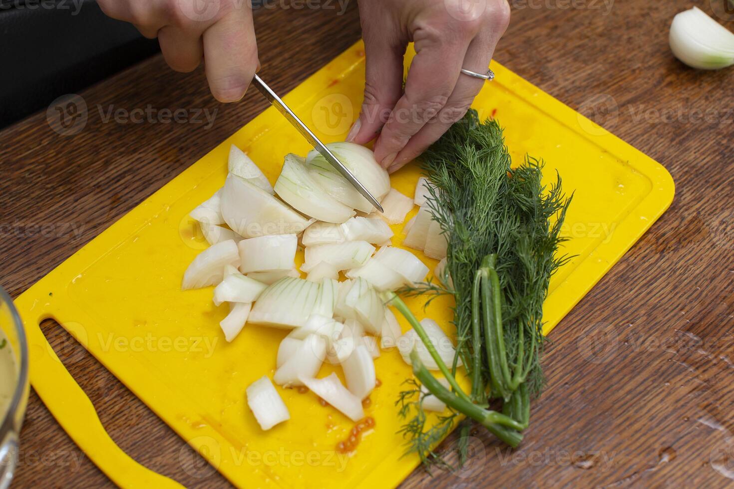 Hands chop onions on a cutting board. Prepare vegetable salad. photo