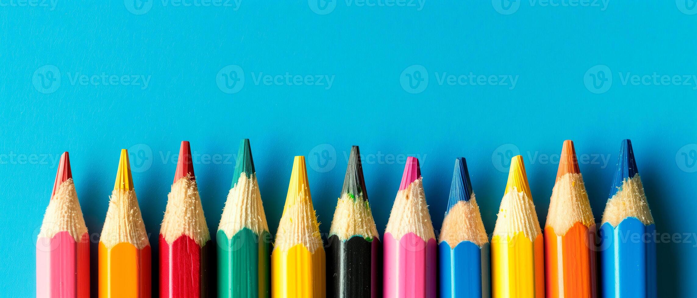 Colourful pencils isolated over blue background. Close up image of vibrant pencils for school with empty space for text. photo