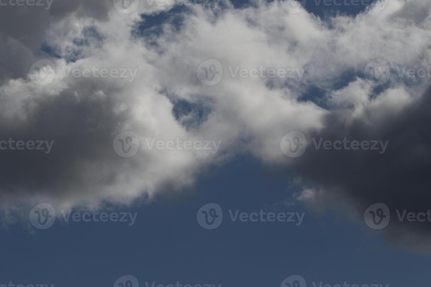 Cloudscape scenery, overcast weather above dark blue sky. Storm clouds floating in a rainy dull day with natural light. White and grey scenic environment background. Nature view. photo