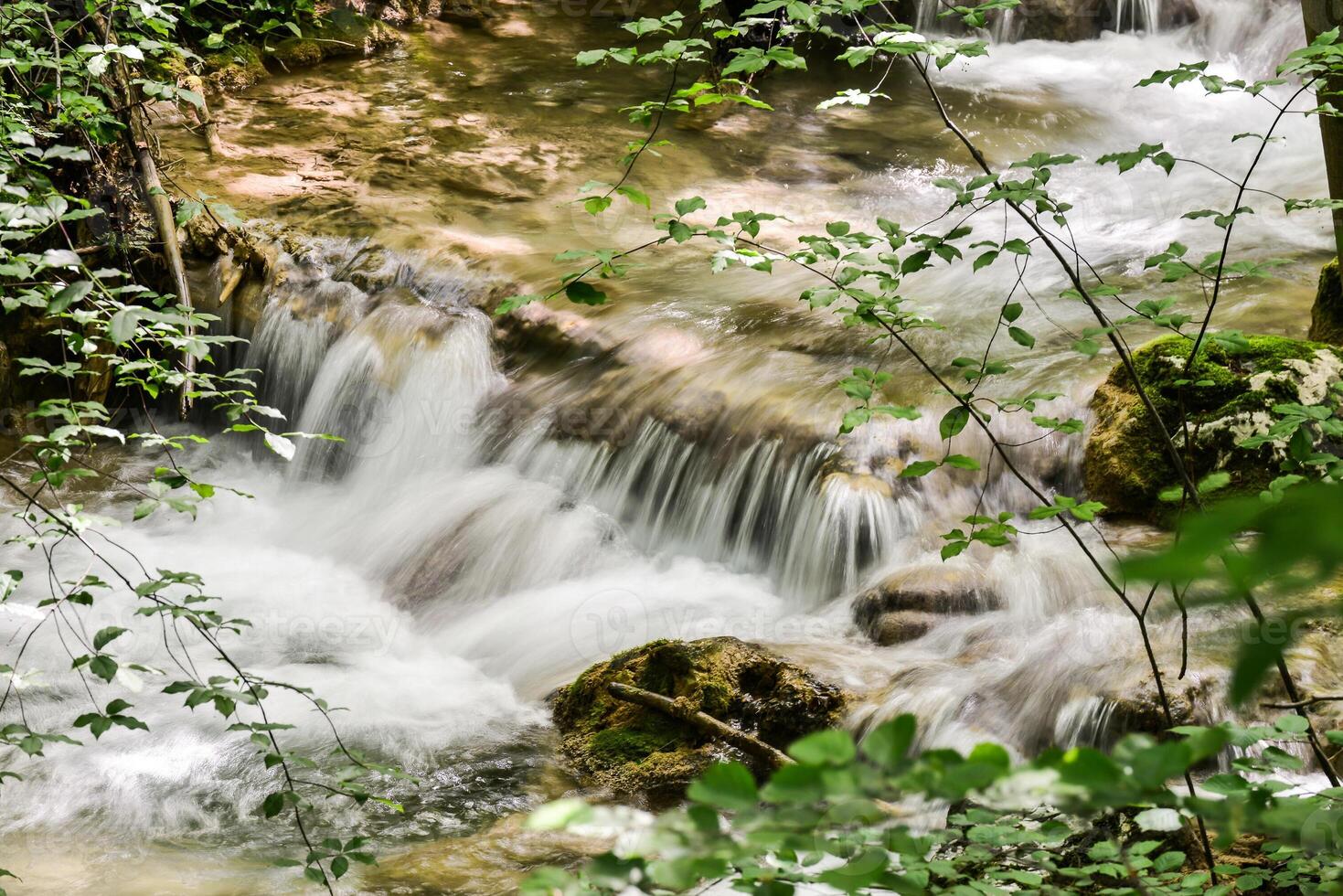 Mountain stream in the forest - long exposure and flowing water photo