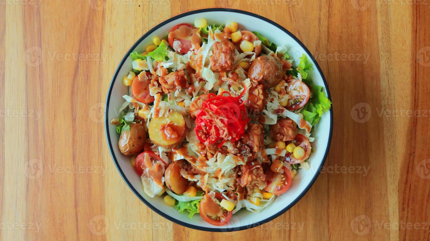 Top view of a bowl of gado-gado sprinkled with peanut sauce, suitable for seasoning satay, ketoprak, and others photo