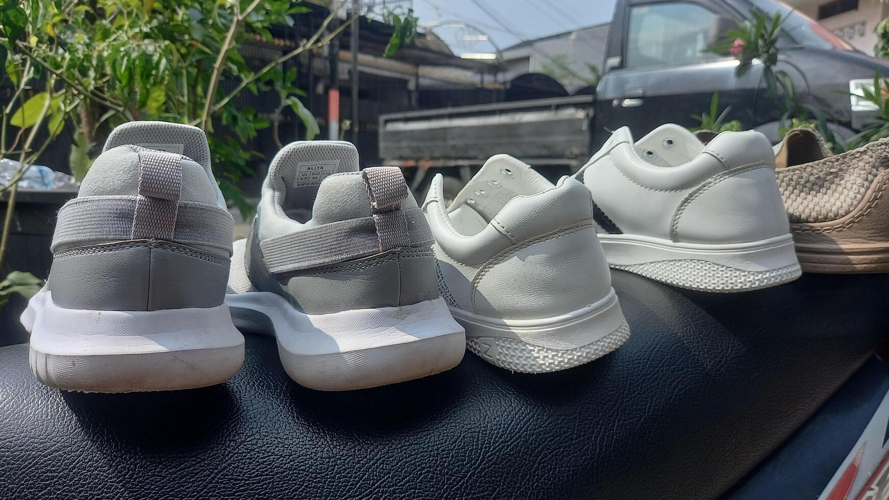 three pairs of white sneakers sitting on top of a car photo