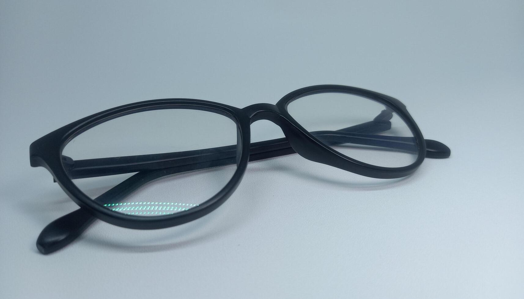 a pair of glasses with black frames on a white surface photo