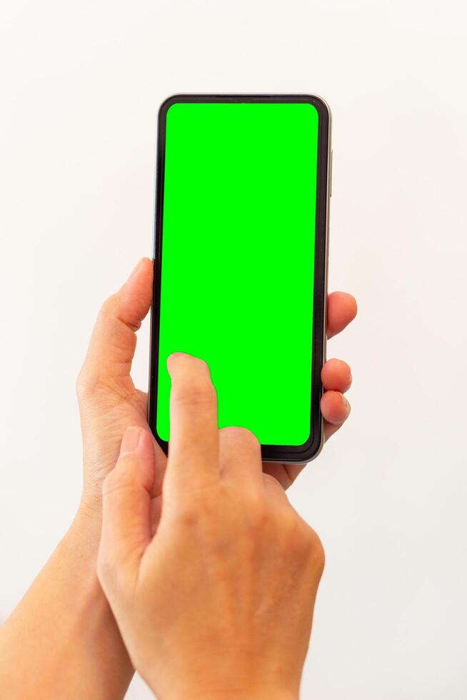 women hand holding smart mobile phone with blank green screen on isolated white background photo
