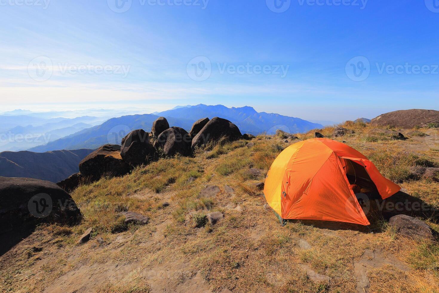 Orange tent on a high hill in the morning photo