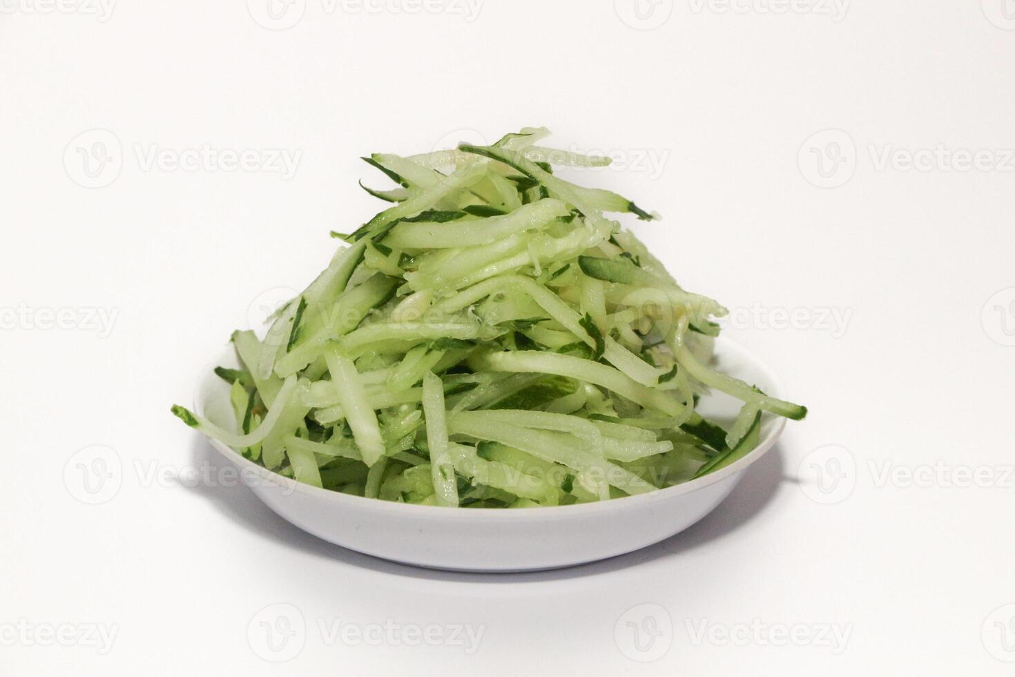 Grated cucumber in a bowl on white background. Healthy vegetarian ingredients photo