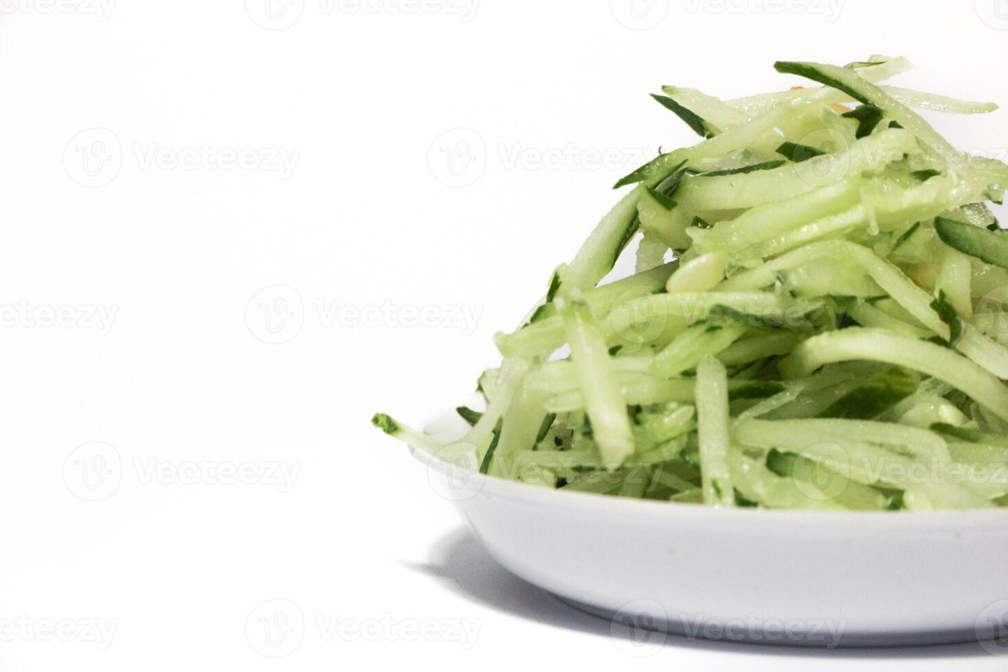 Grated cucumber in a bowl on white background. Healthy vegetarian ingredients photo