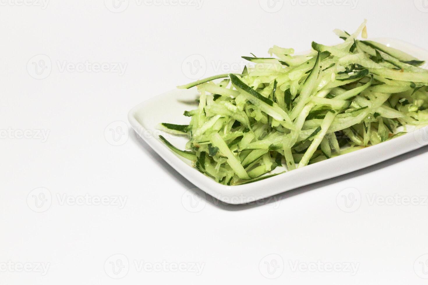 Grated cucumber in a bowl on white background. Healthy vegetarian ingredients photo