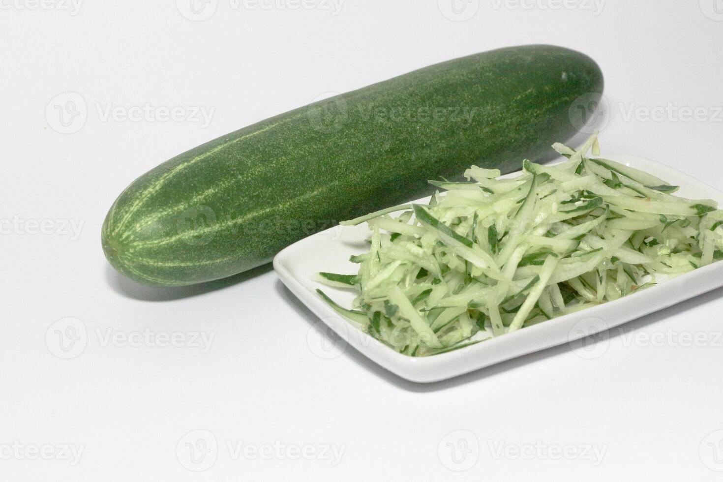Grated cucumber in a bowl on white background. Healthy vegetarian ingredients photo