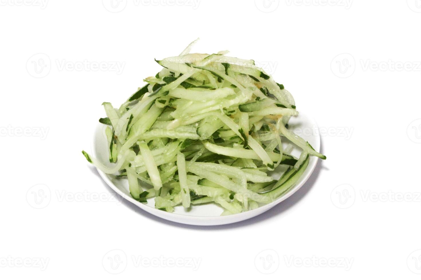 Grated cucumber in a bowl on white background. Healthy vegetarian ingredients photo