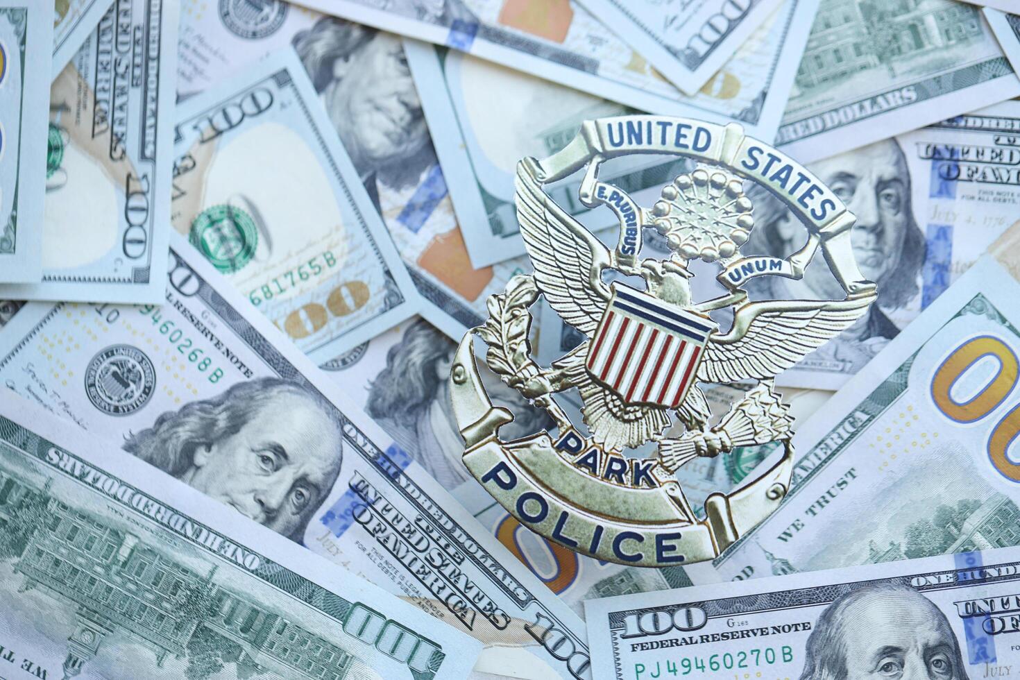 KYIV, UKRAINE - MARCH 9, 2024 US United States Park Police badge on many US hundred dollar bills photo