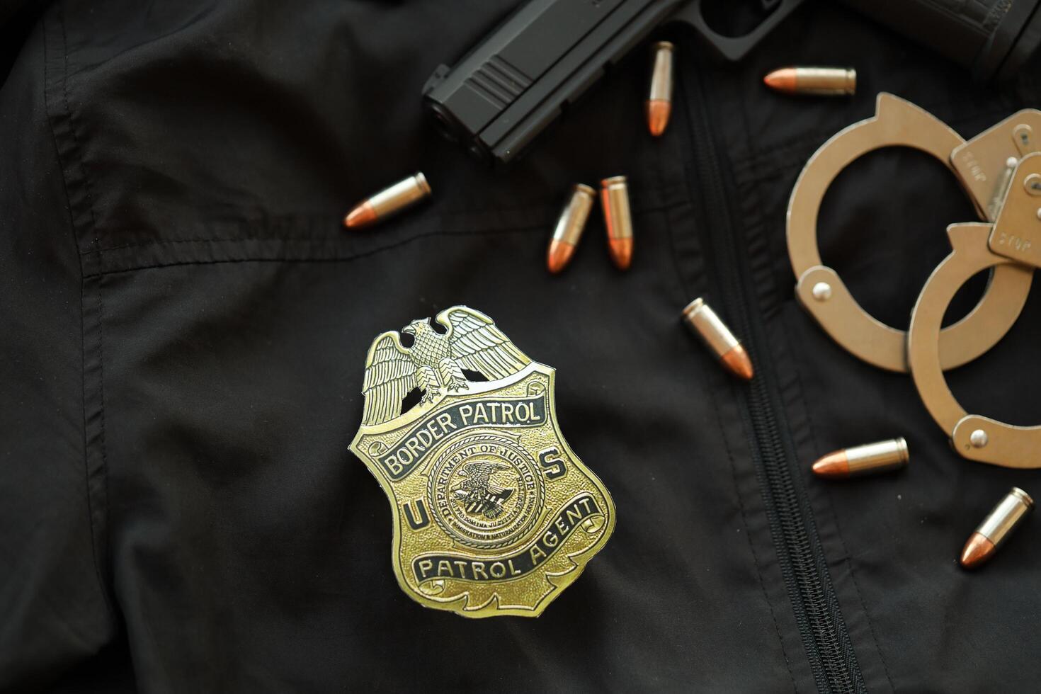 KYIV, UKRAINE - MARCH 9, 2024 US Border Patrol Agent badge on black jacket uniform with gun, bullets and handcuffs photo