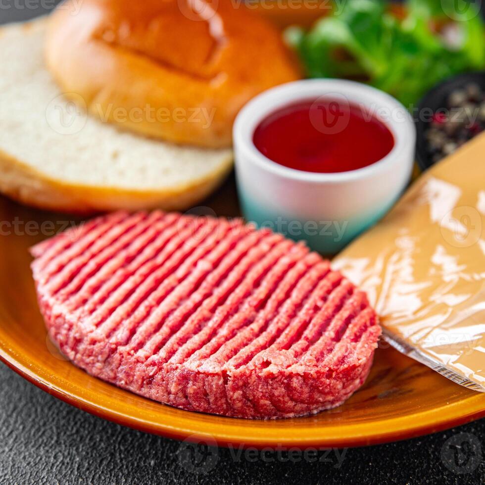 hamburguesa conjunto crudo chuleta, bollo, queso, tomate salsa, verduras Fresco Cocinando aperitivo comida comida bocadillo en el mesa Copiar espacio comida antecedentes rústico foto